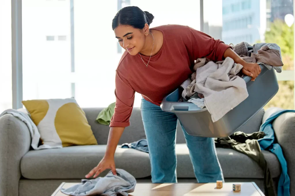 A woman picking up the clothes in the living room