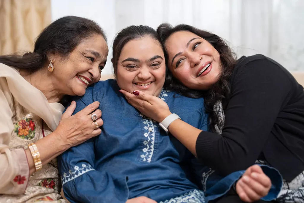 A disabled woman being hugged by her support workers